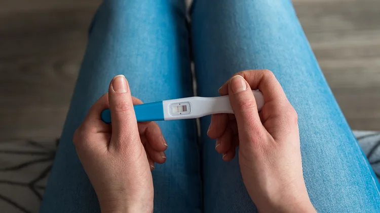 Woman sitting and holding a positive pregnancy test