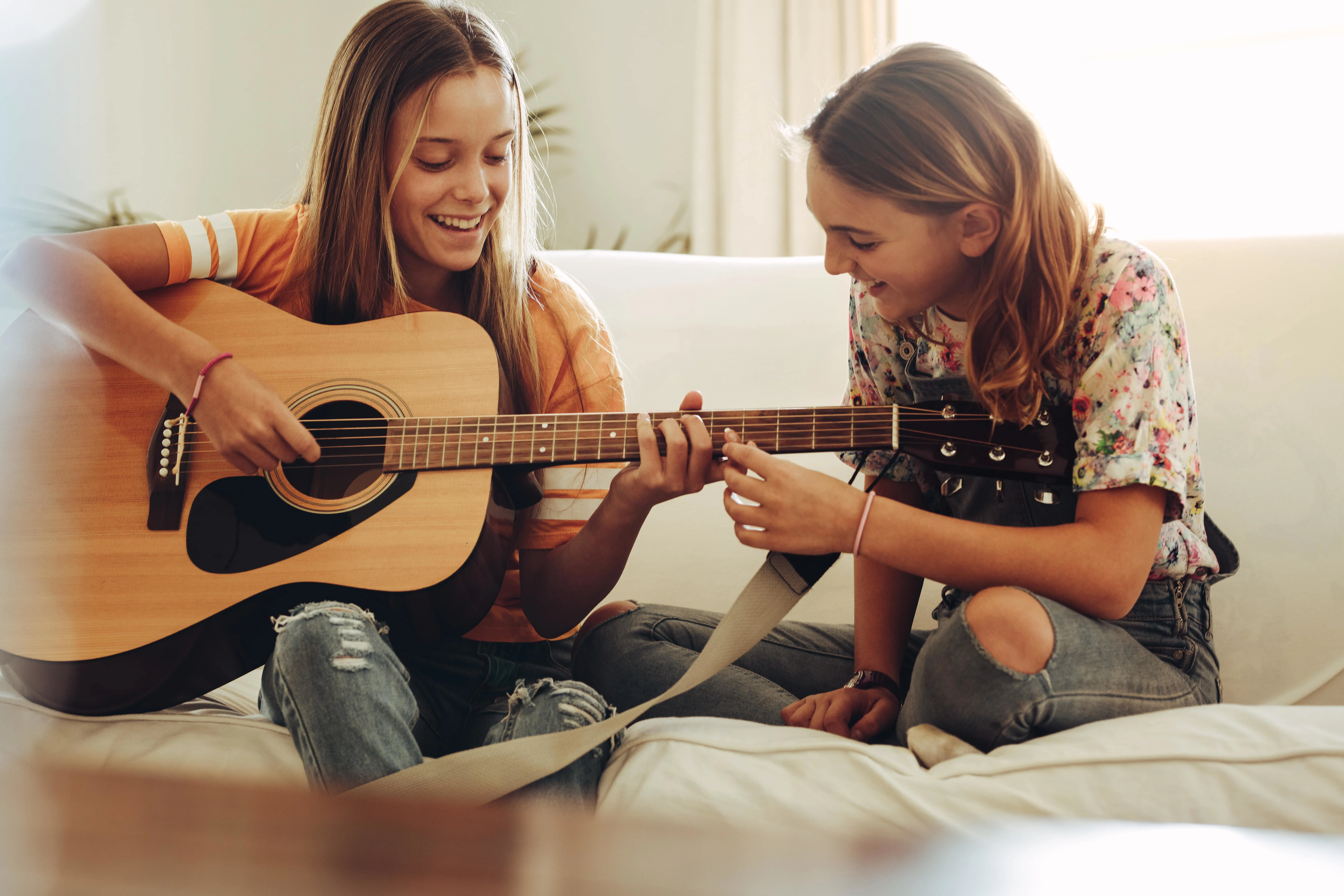 Two girls playing guitar on the couch