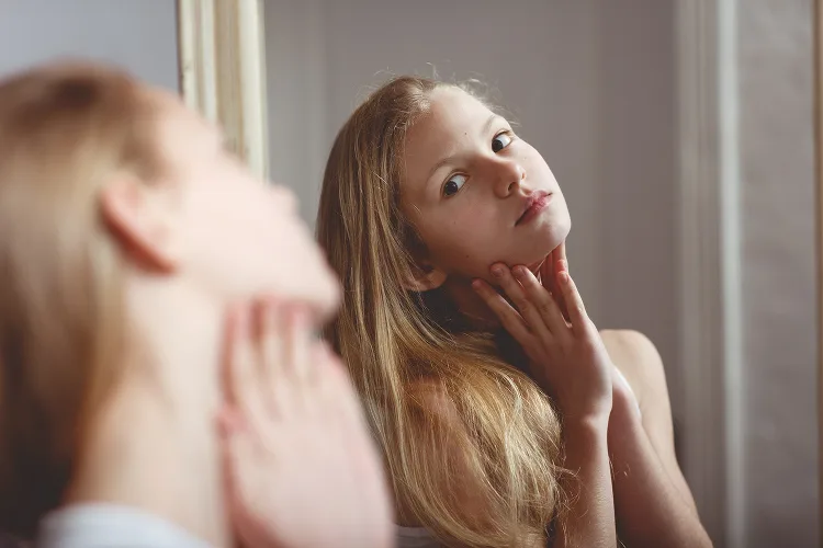 Young girl looking herself in the mirror
