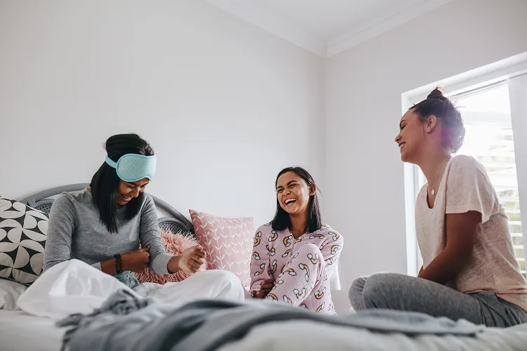 Girls sitting on a bed and laughing