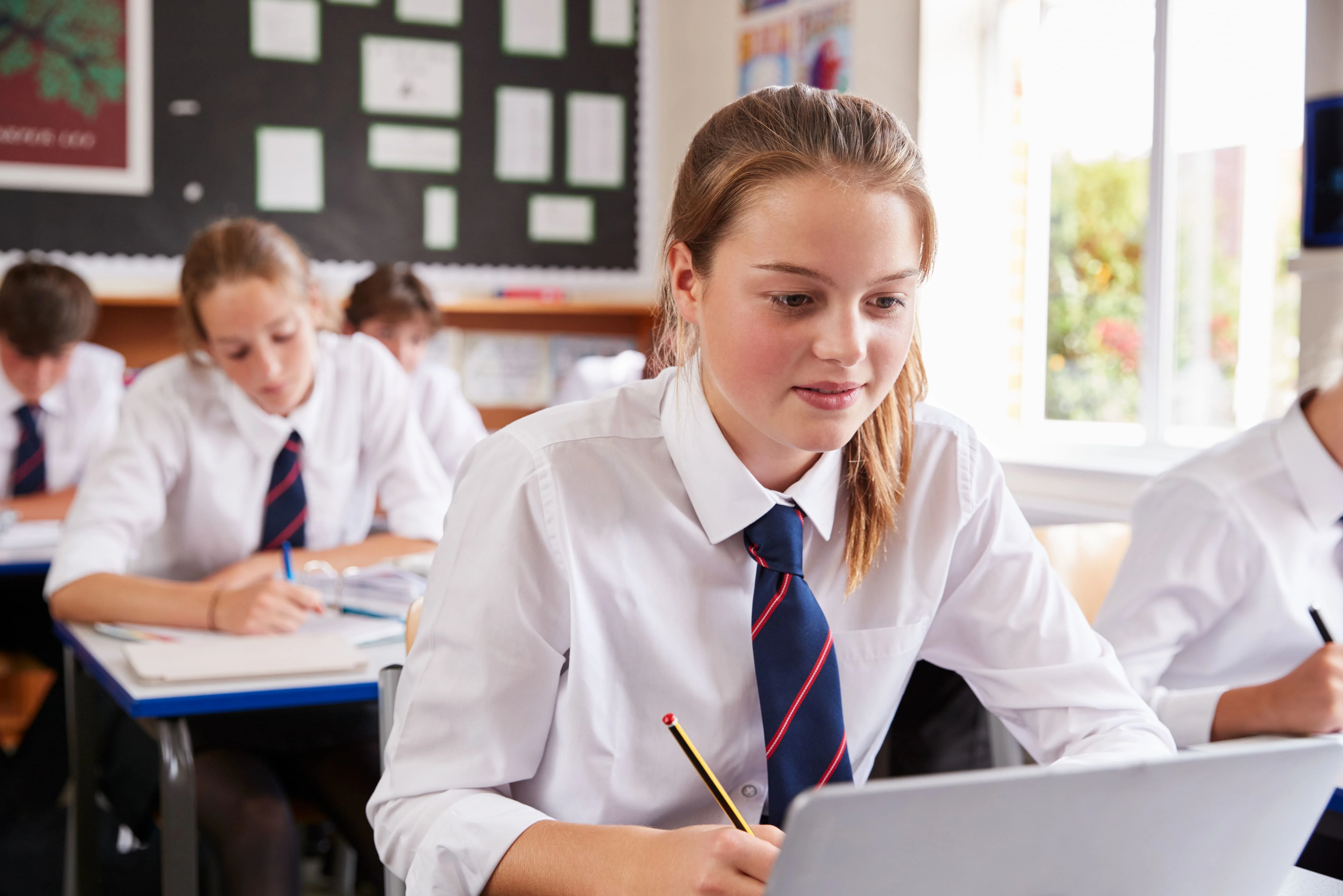 Girl in classroom looking at her laptop