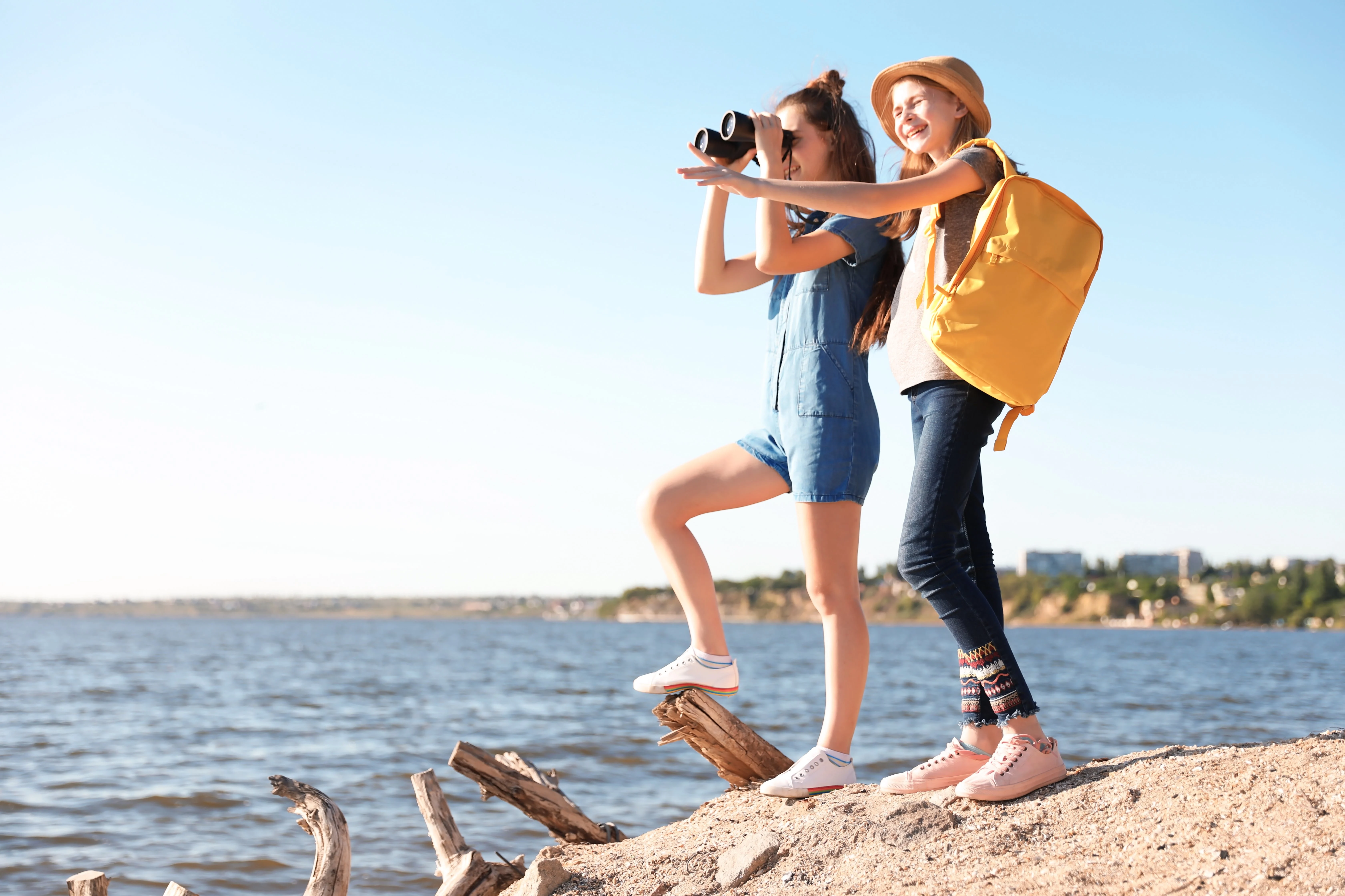 Two girls at the beach looking through binoculars