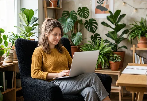  Woman casually browsing information on her phone/laptop in a comfortable home environment.