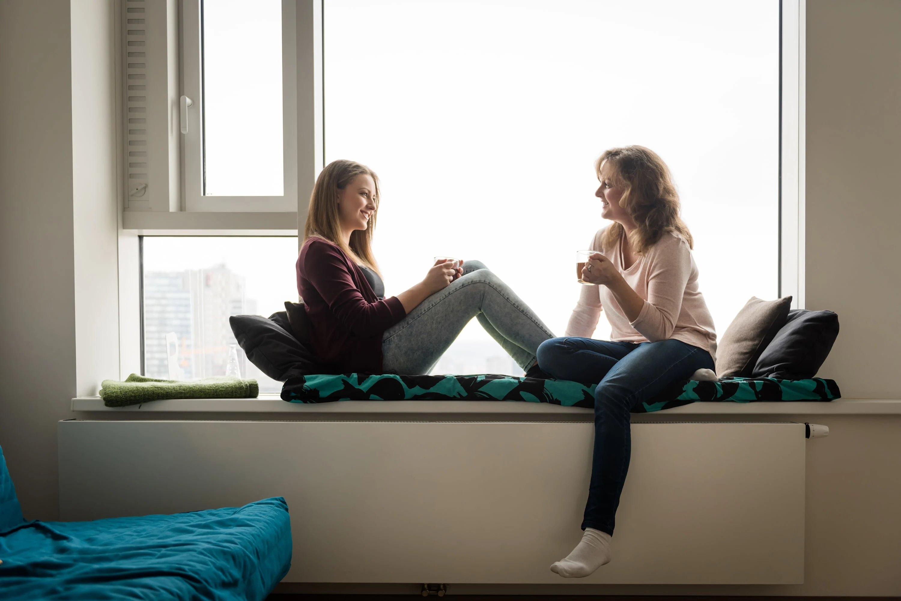 Mother and daughter sitting on a window seat