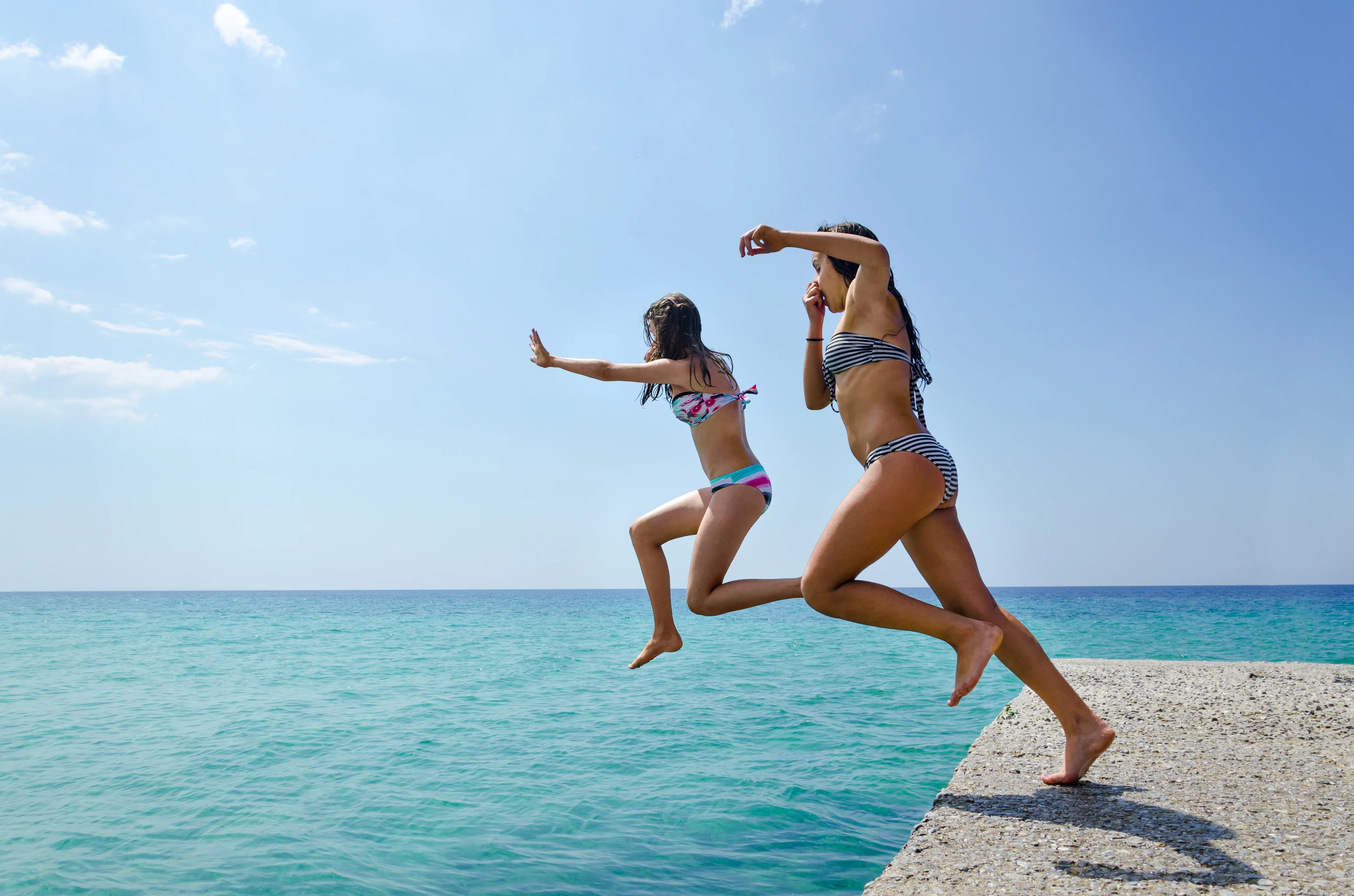 Two girls jumping into the sea