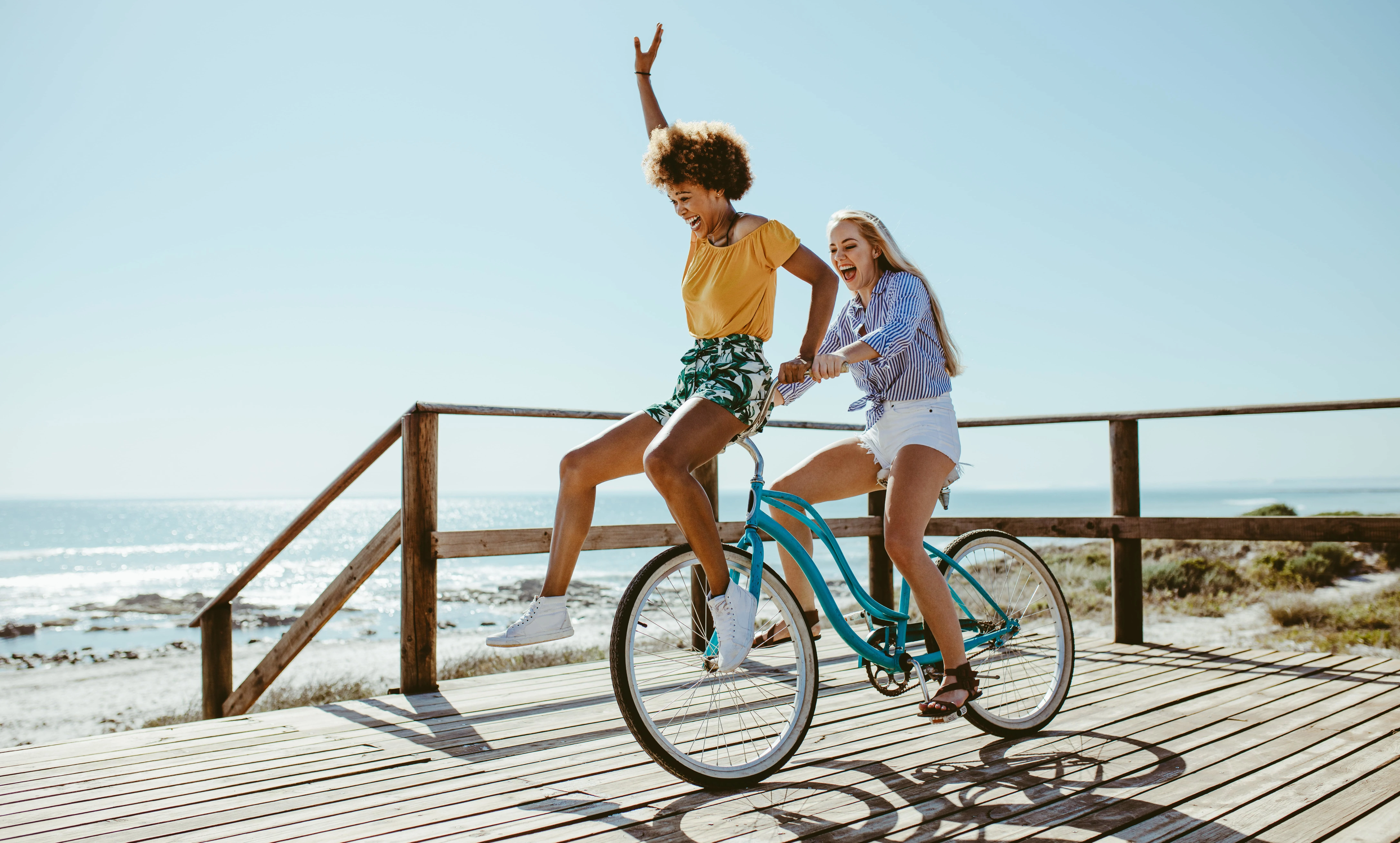 Two girls having fun on a bike near to the sea