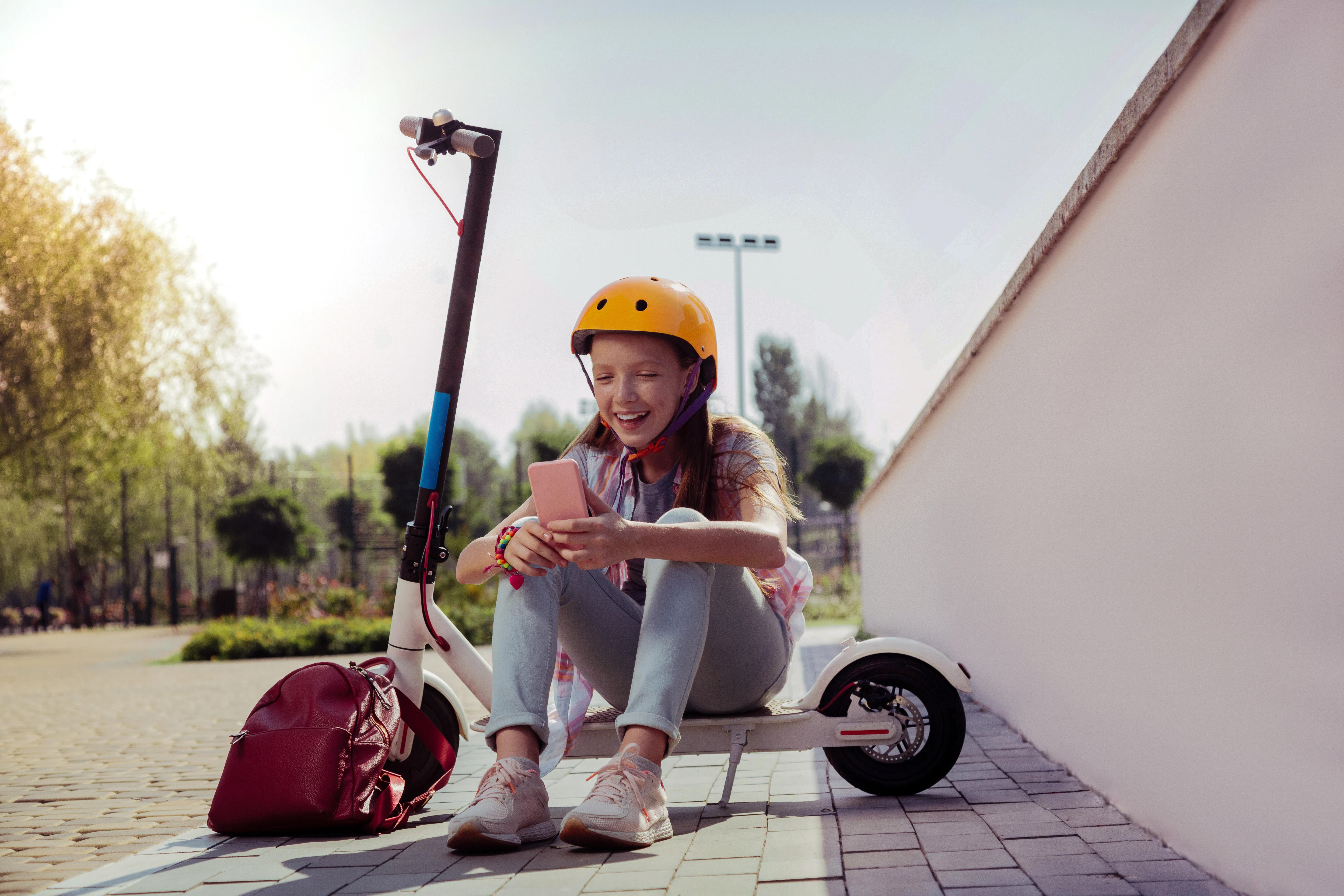 Girl sitting on a scooter and looking at her phone