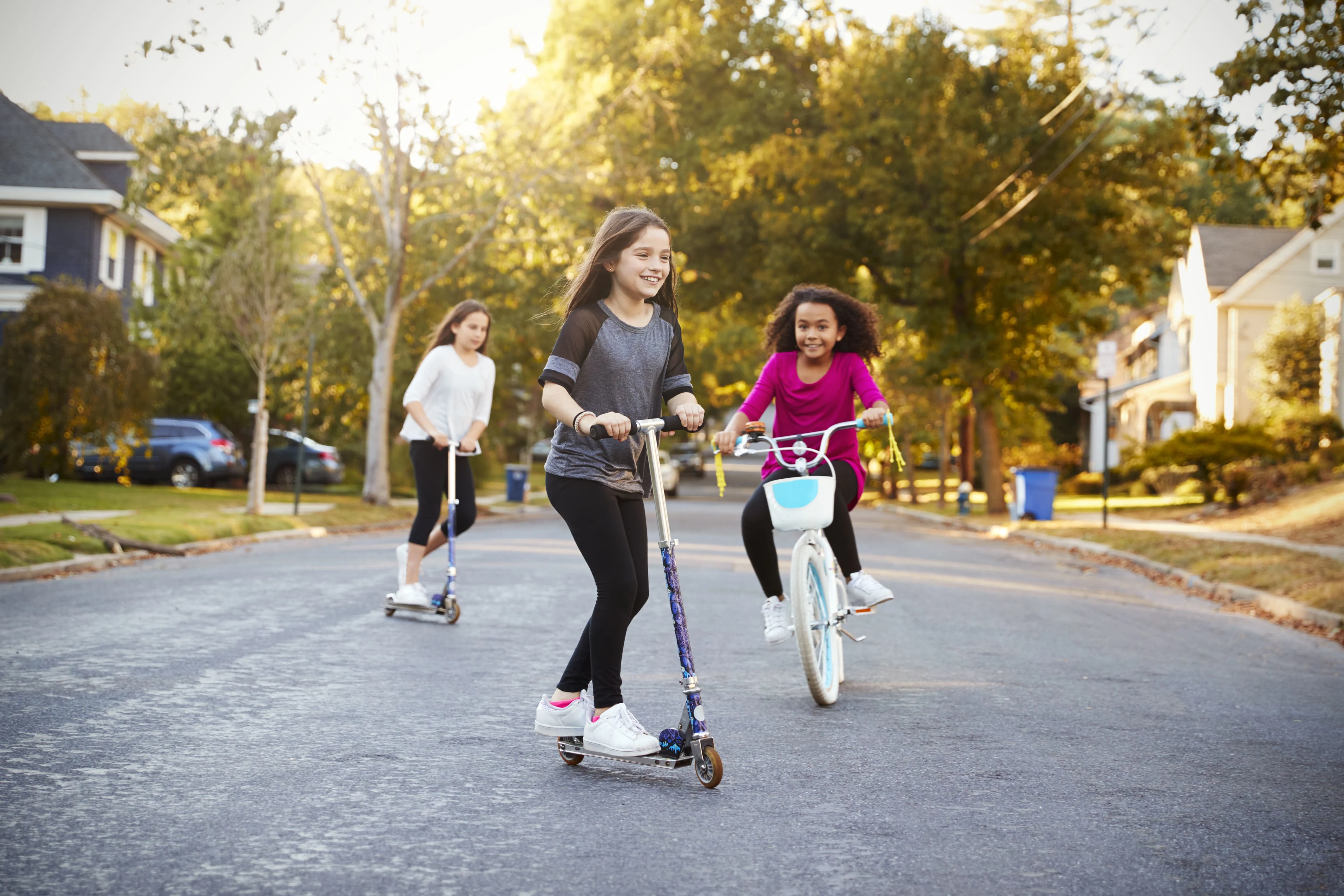 Young girls riding scooters and bicycles