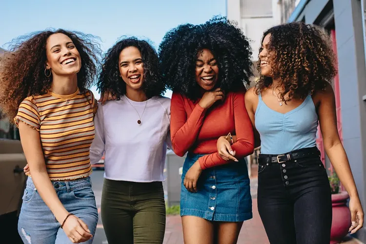 Four women laughing while walking