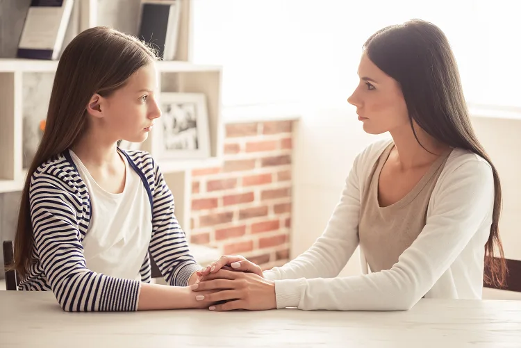 Daughter and mother holding hands and looking each other in the eyes