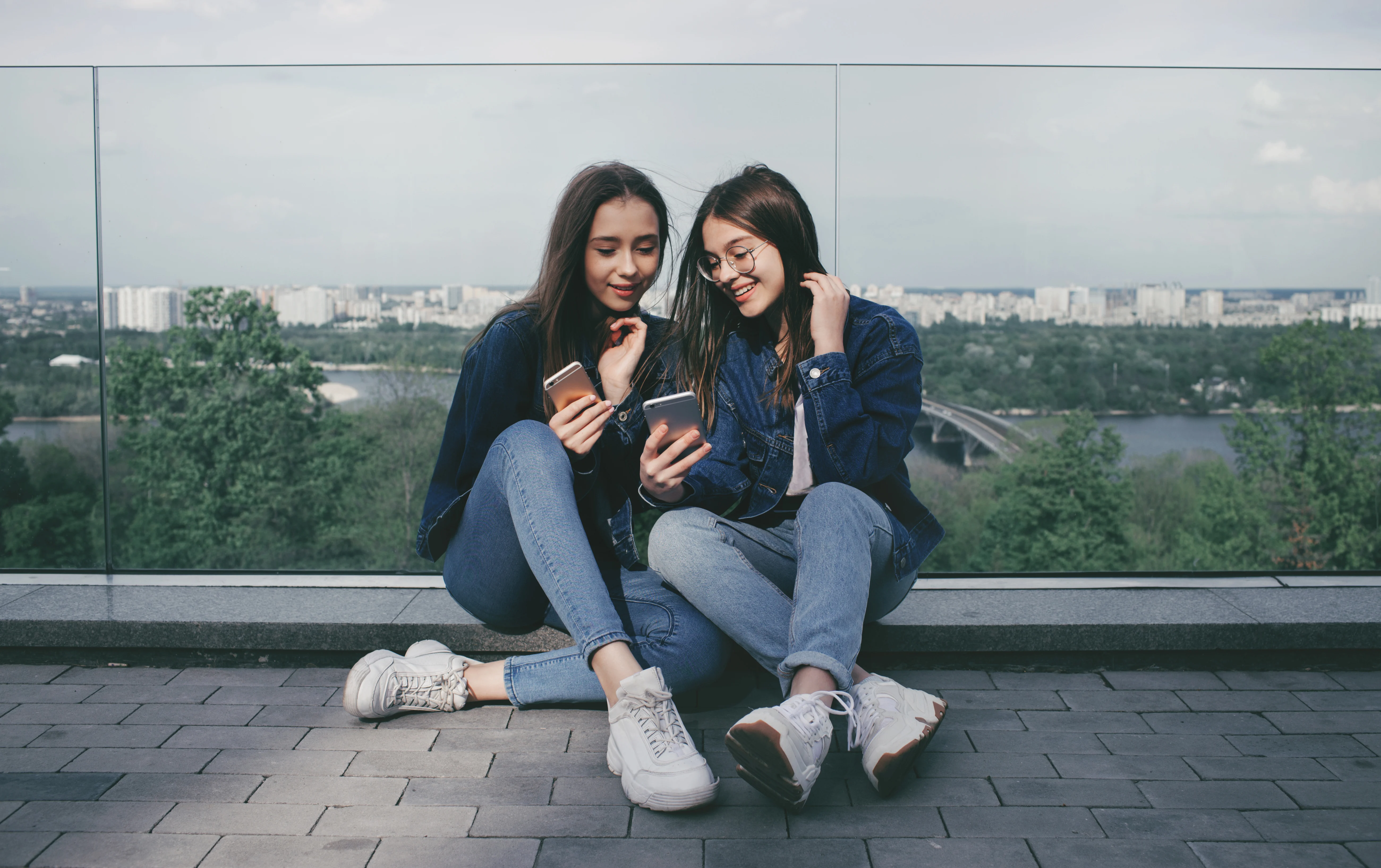 Girls sitting against a glass fence