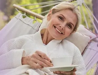 Smiling middle-aged woman lying in a hammock