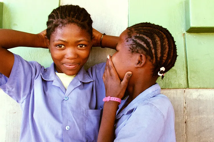 Portrait of a two girls smiling in front of a light green wall