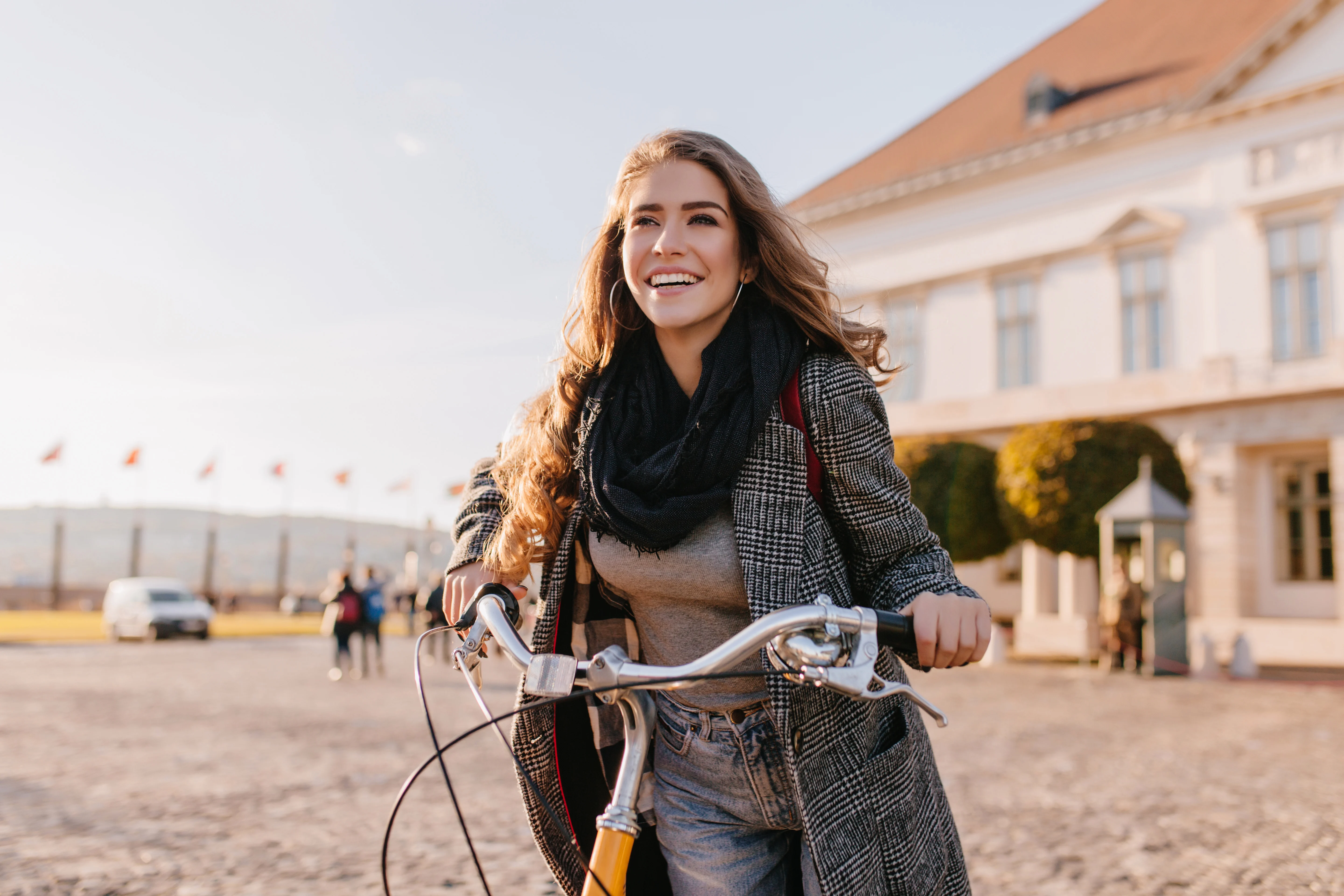 Woman holding her bike and smiling while looking at the distance