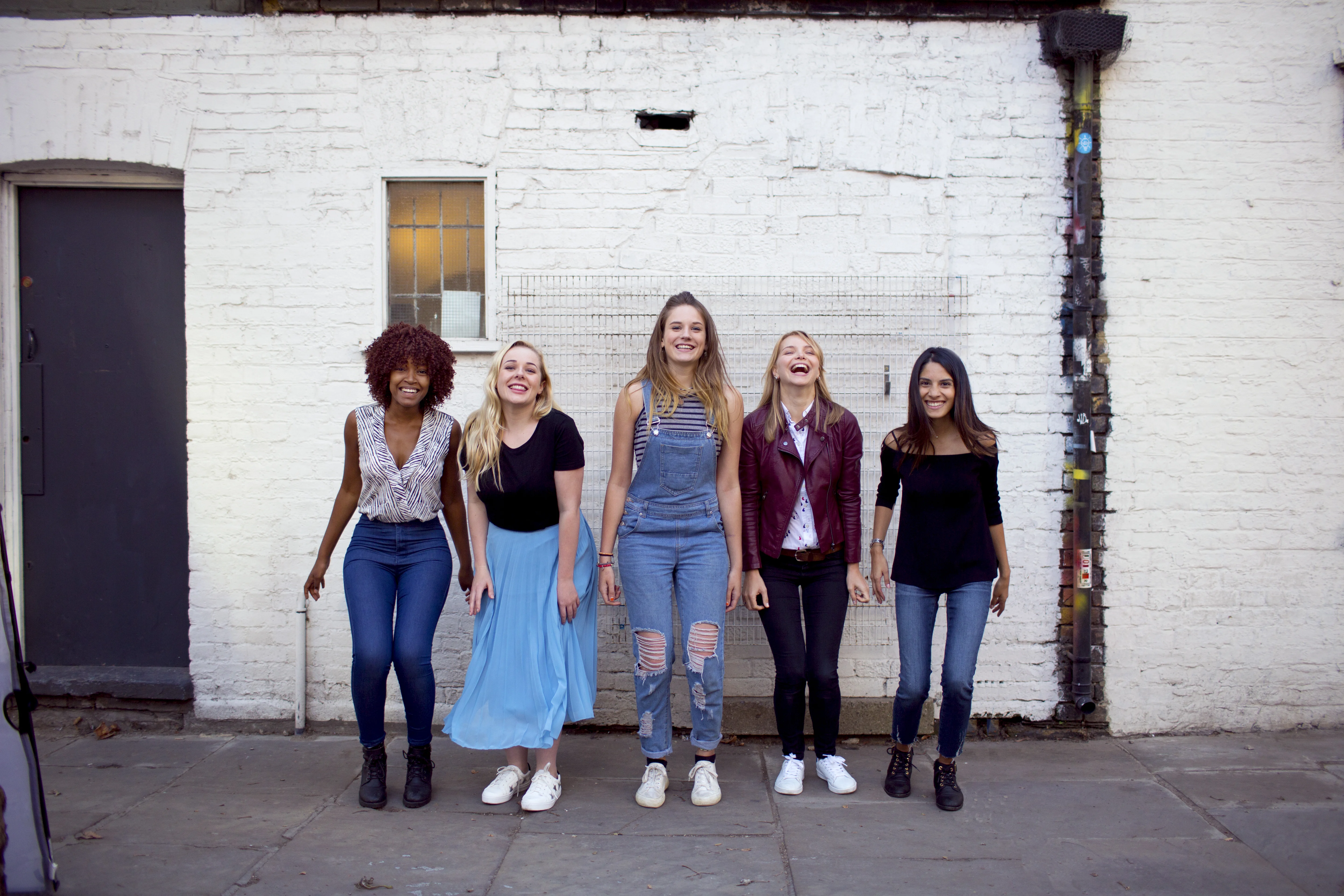 Girls standing in front of a white brick wall and laughing