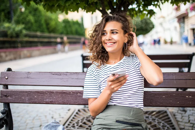 Girls smiling and looking at the distance while sitting on a bench
