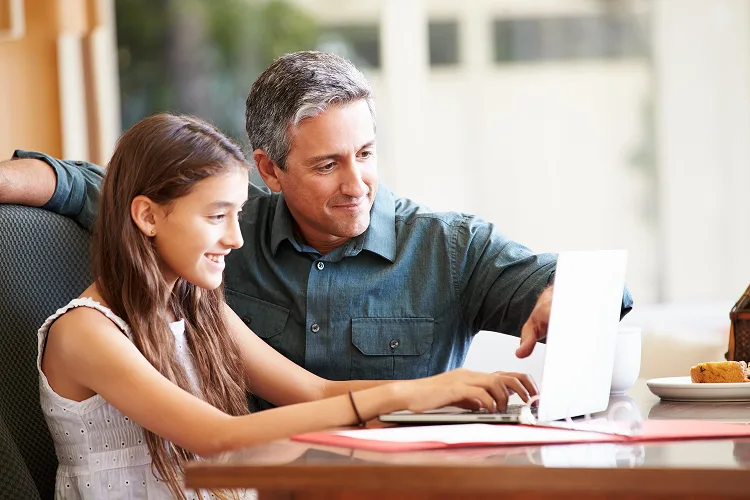 Daughter and father looking at a laptop screen