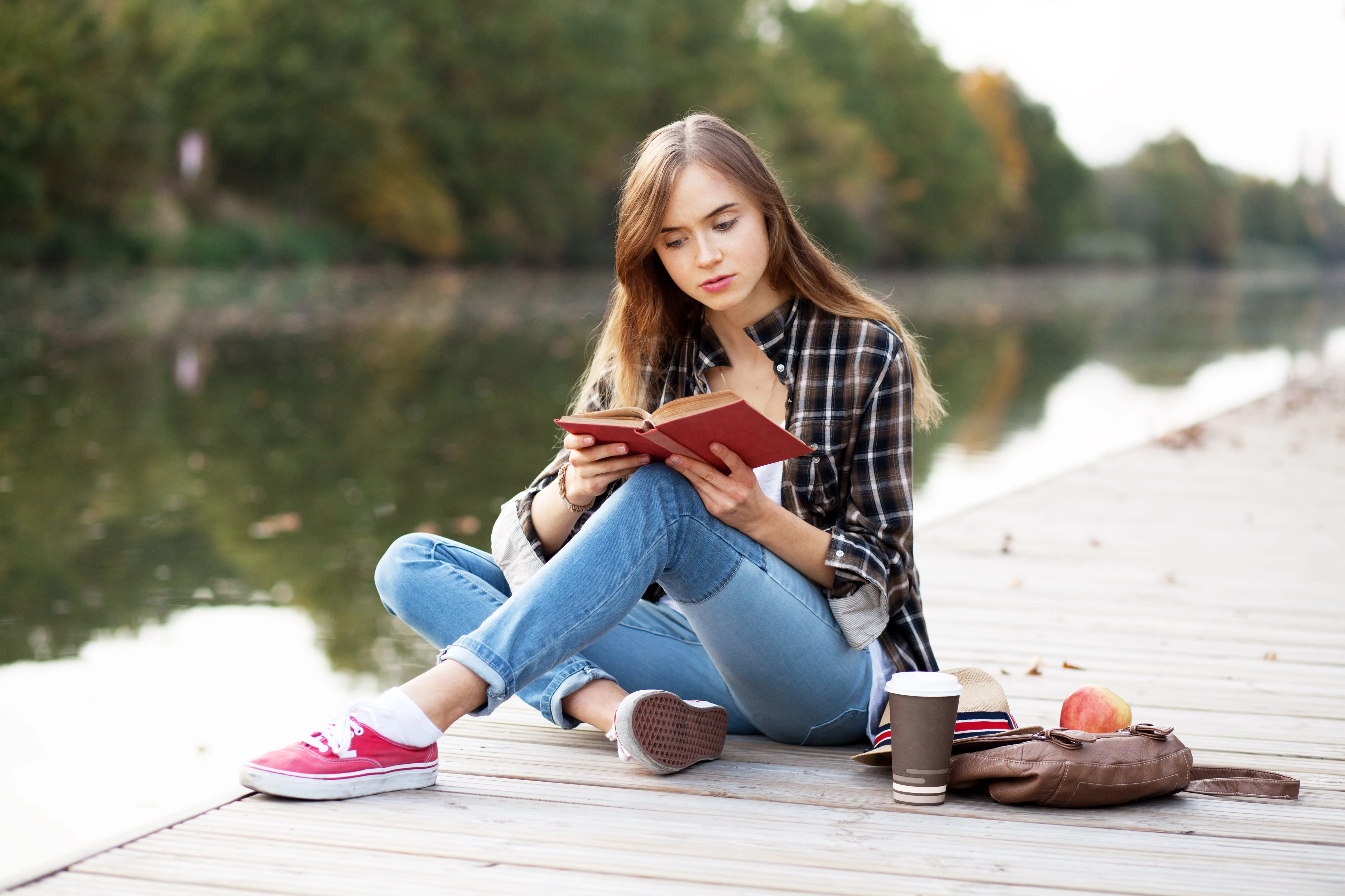Girl reading a book while sitting on a dock