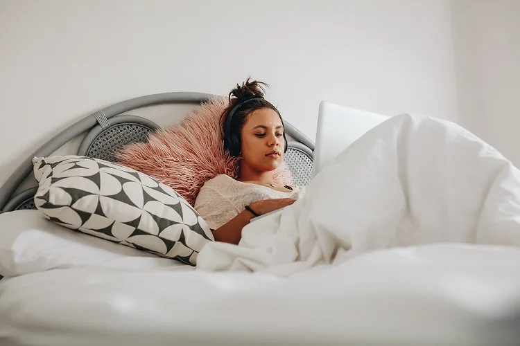 A girl lying in bed and spending time on her laptop