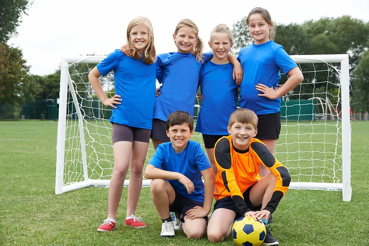 Young gilrs and boys group photo in front of a football goal