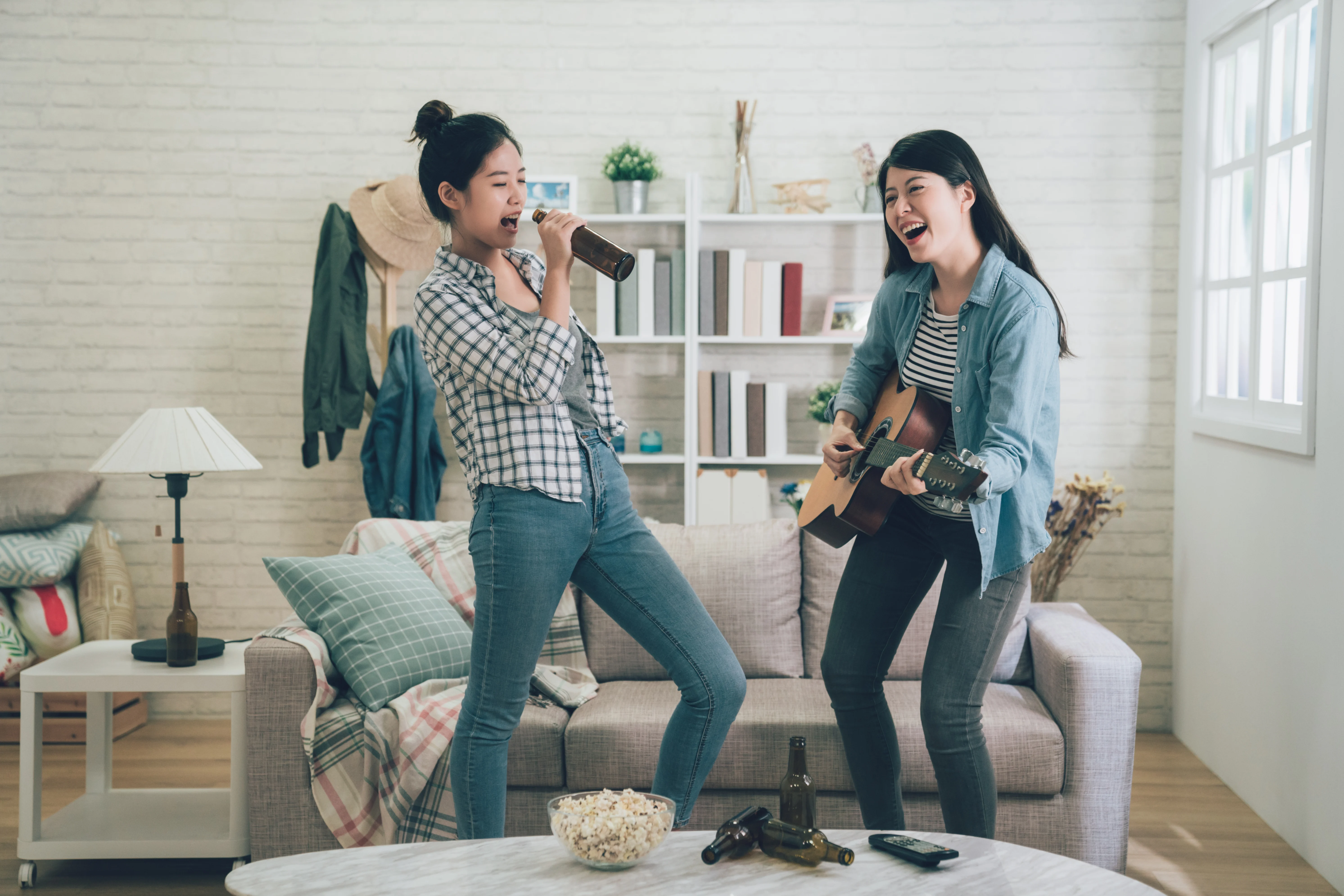 Two girls singing and playing a guitar in the living room