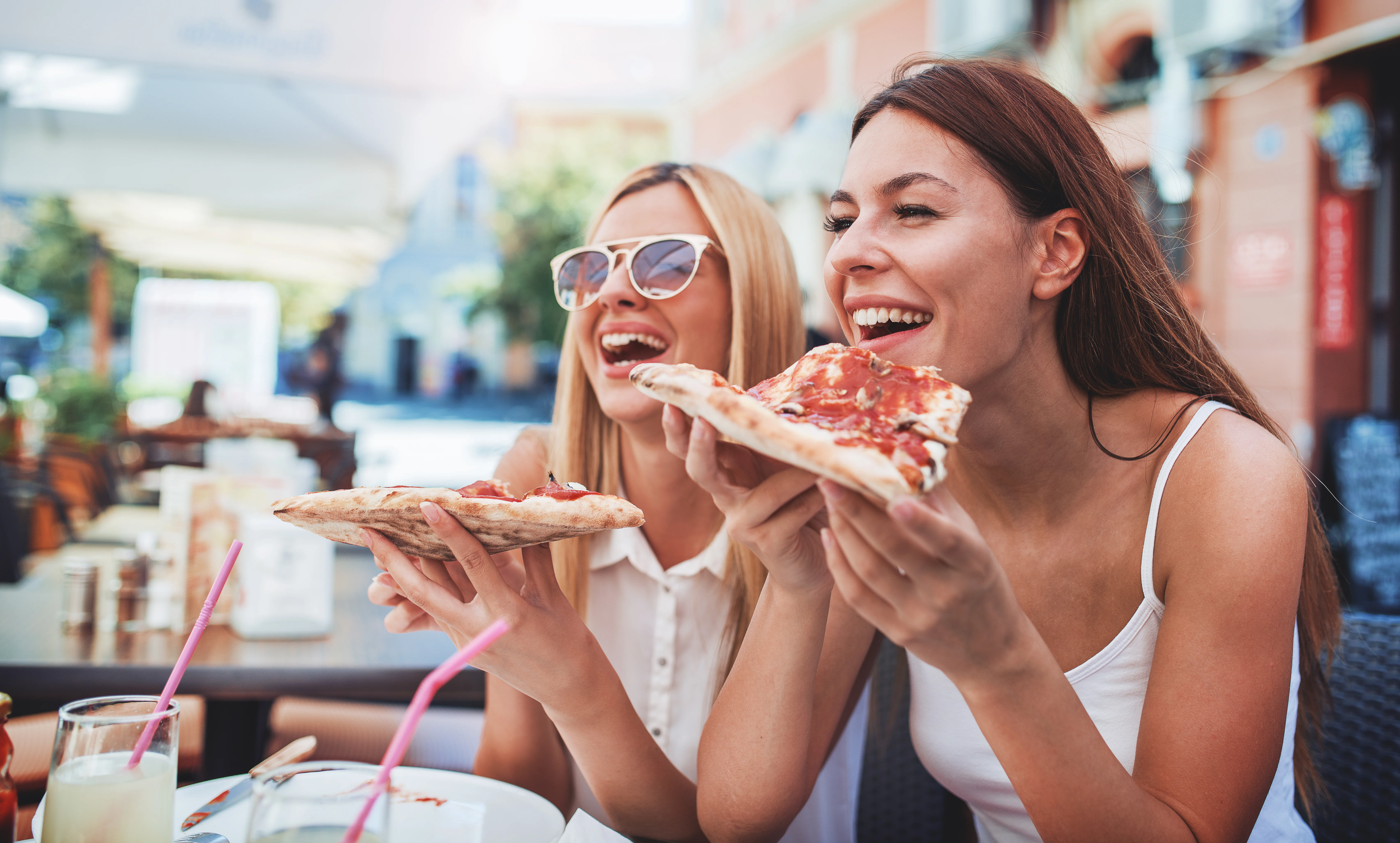 Two women eating pizza and laughing