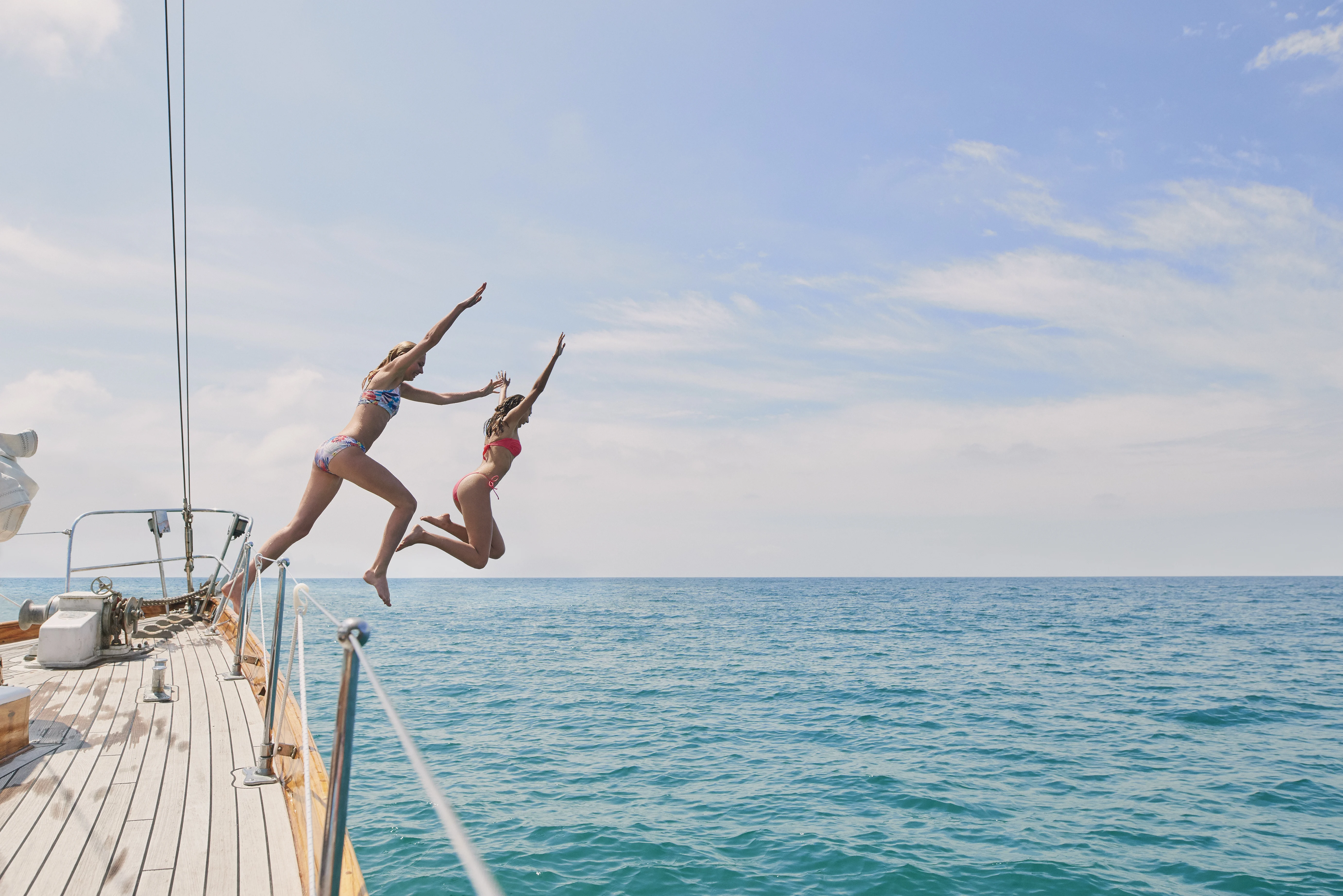 Two girl jumping into the sea from a boat