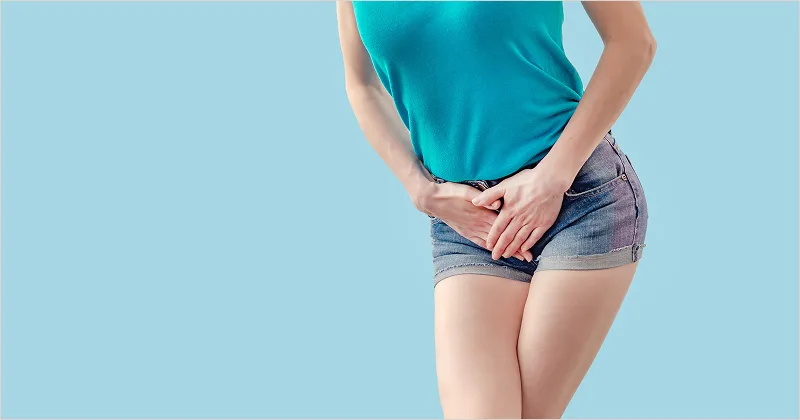 A woman holding her lower belly with a pressing need to urinate