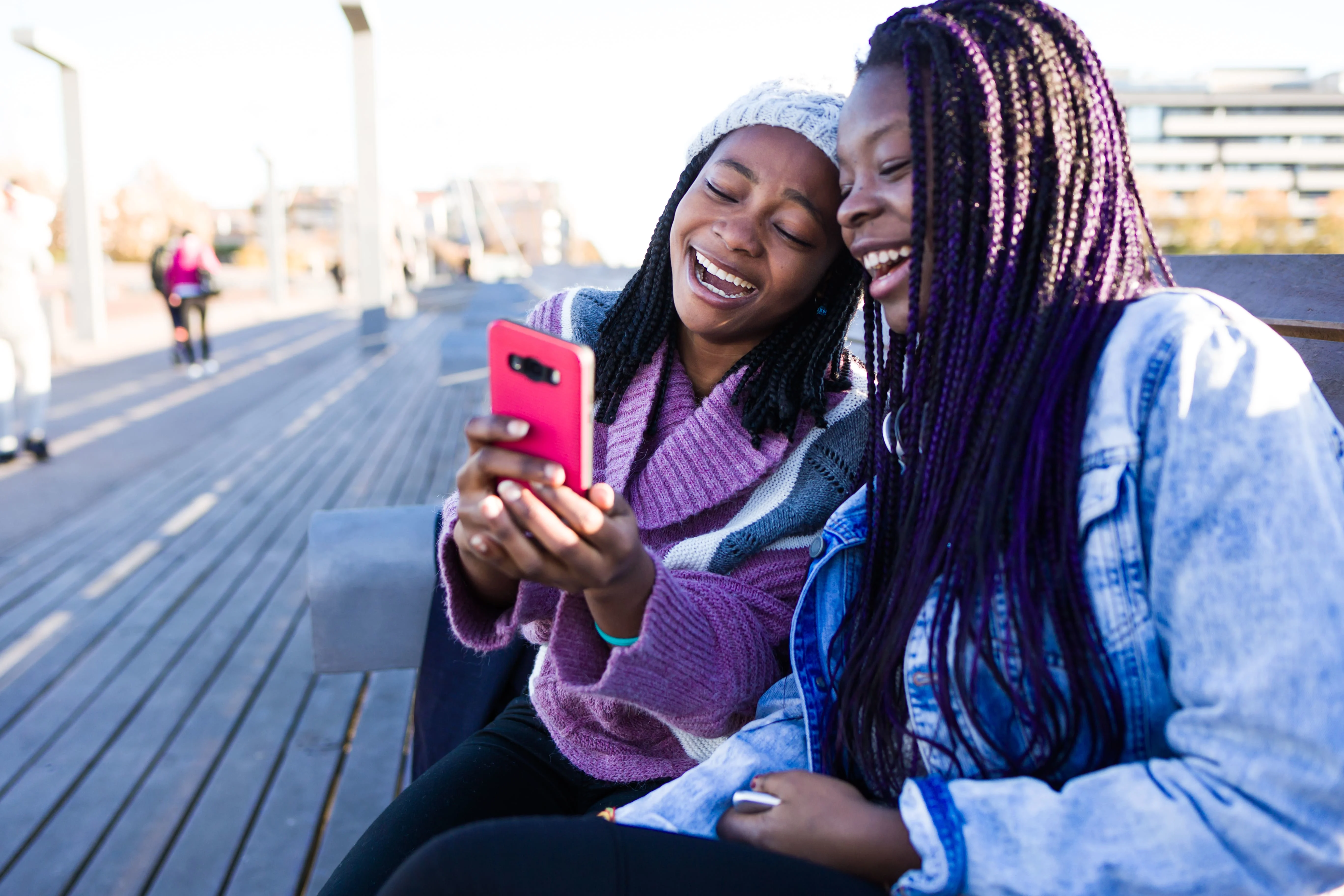 Two girls laughing while looking at a phone