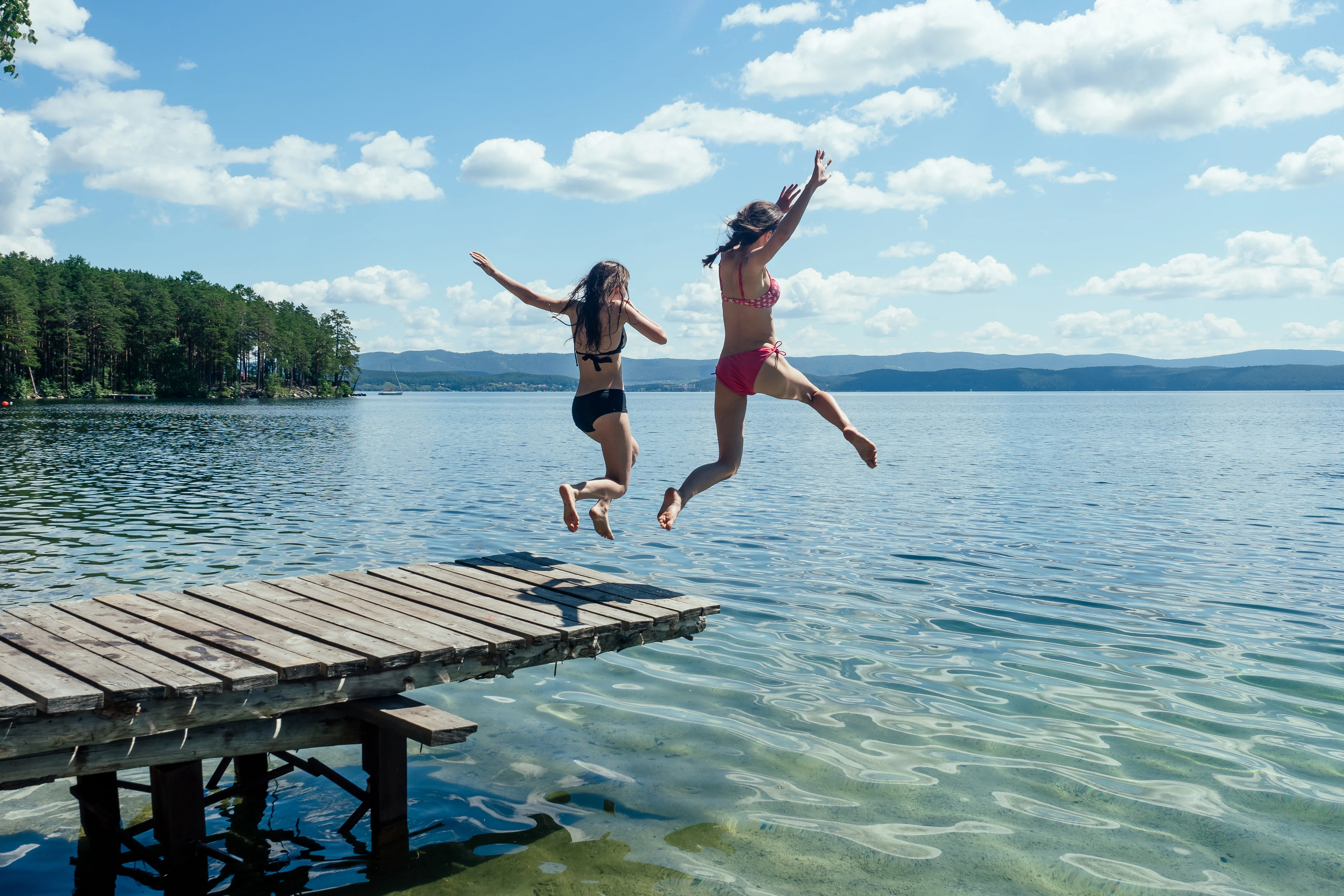 Two women jumping into a lake