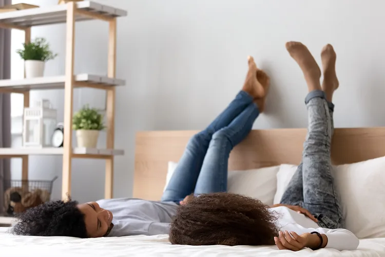 Daughter and mother lying and bed with their legs in the air