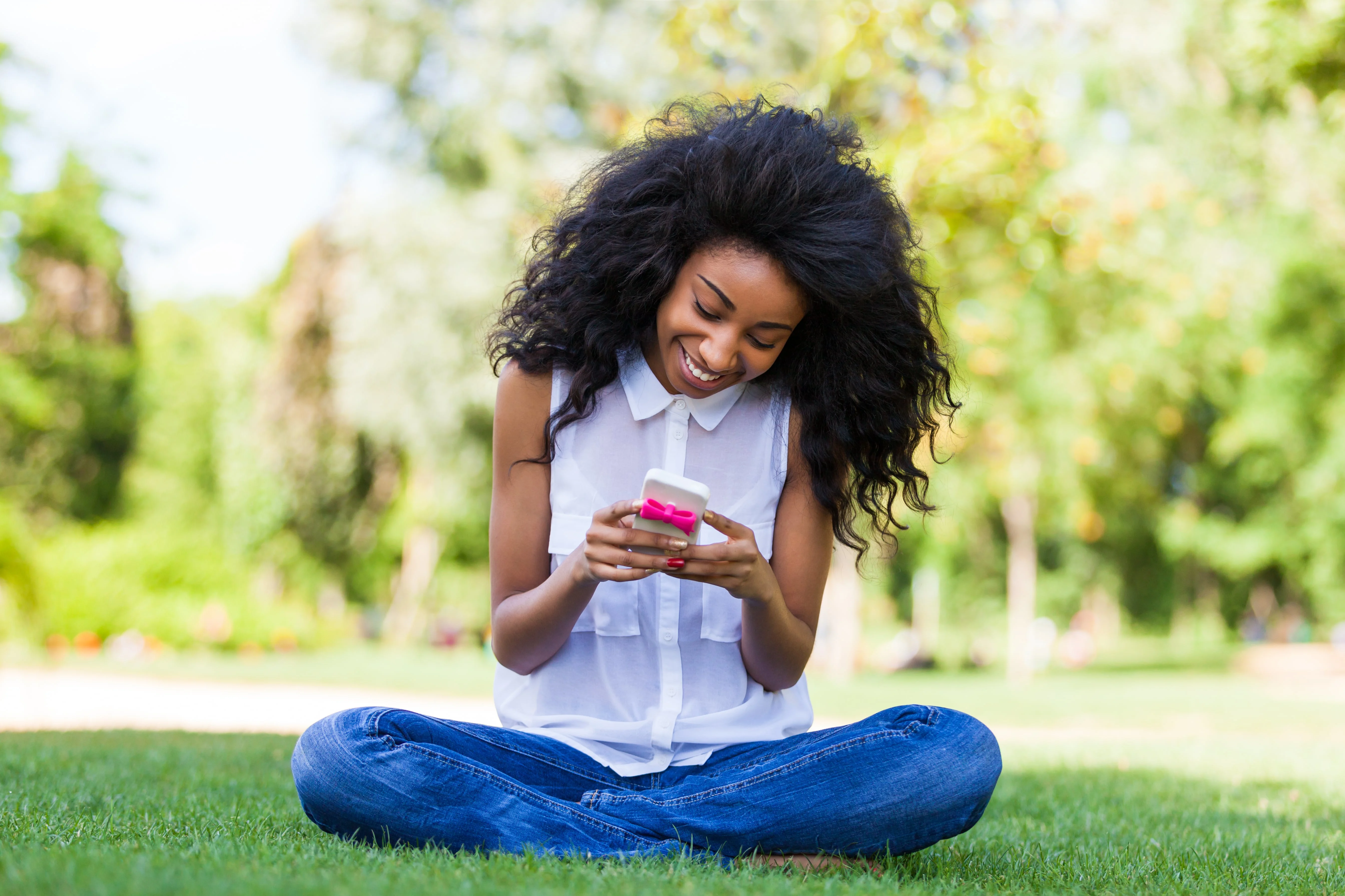 Girl sitting on grass and looking at her phone