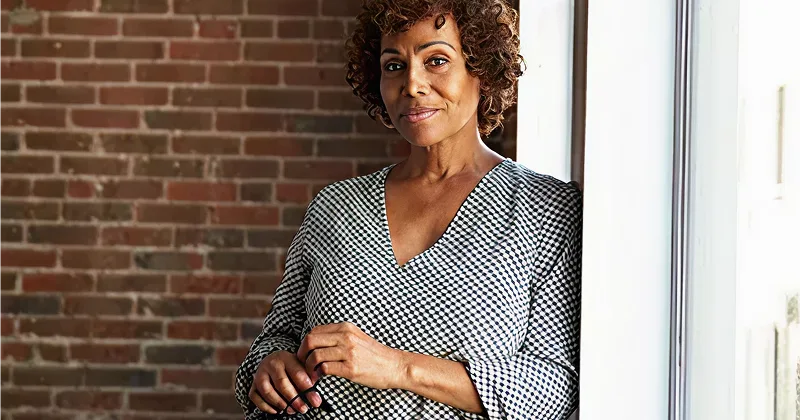 Smiling middle-aged woman standing near the window