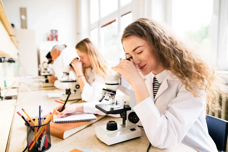 Young students learning on microscopes