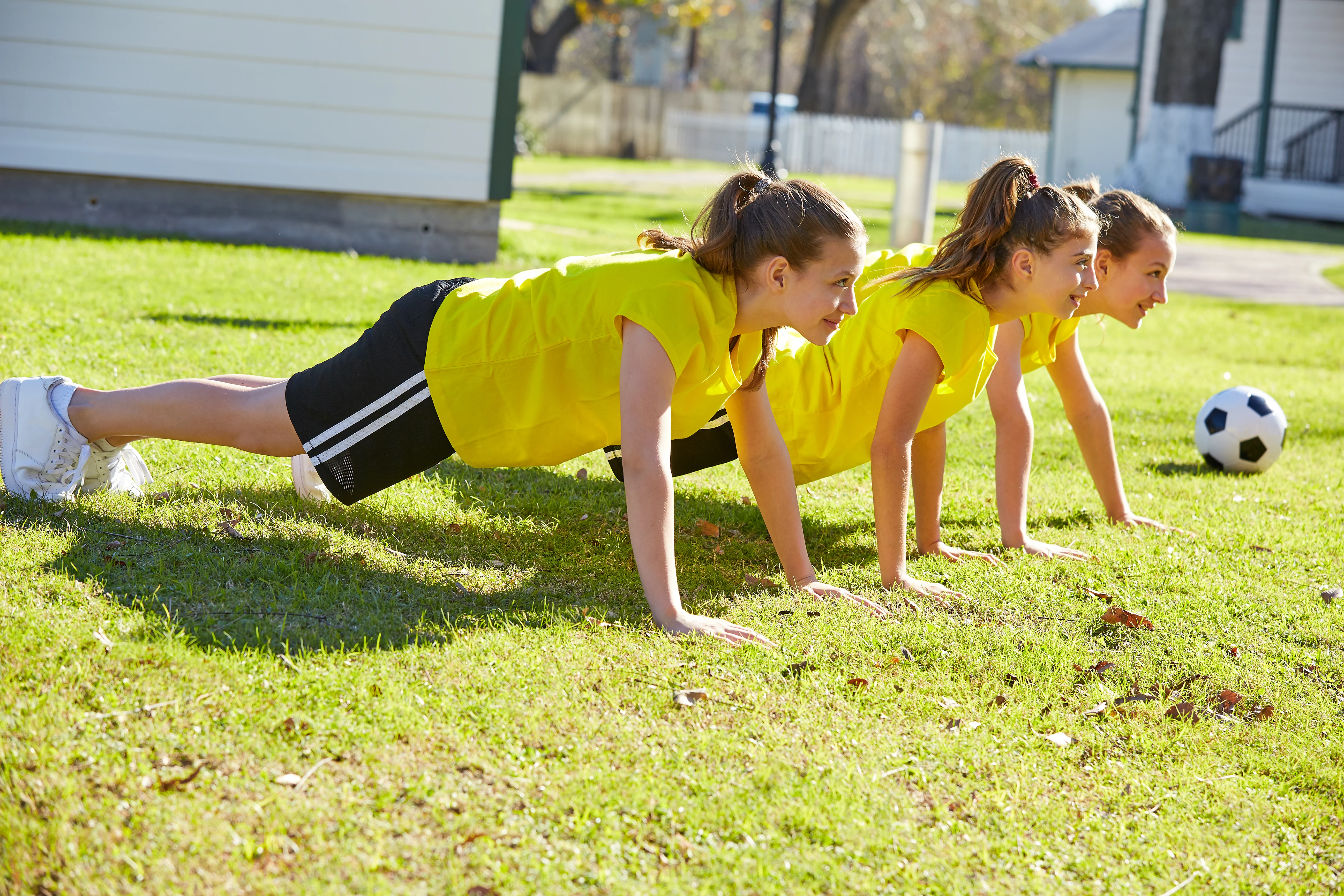 Girls in plank position on a football field