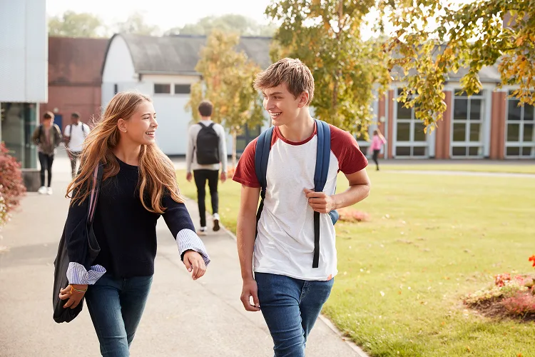 Teen boy and girl sitting on a bench outside
