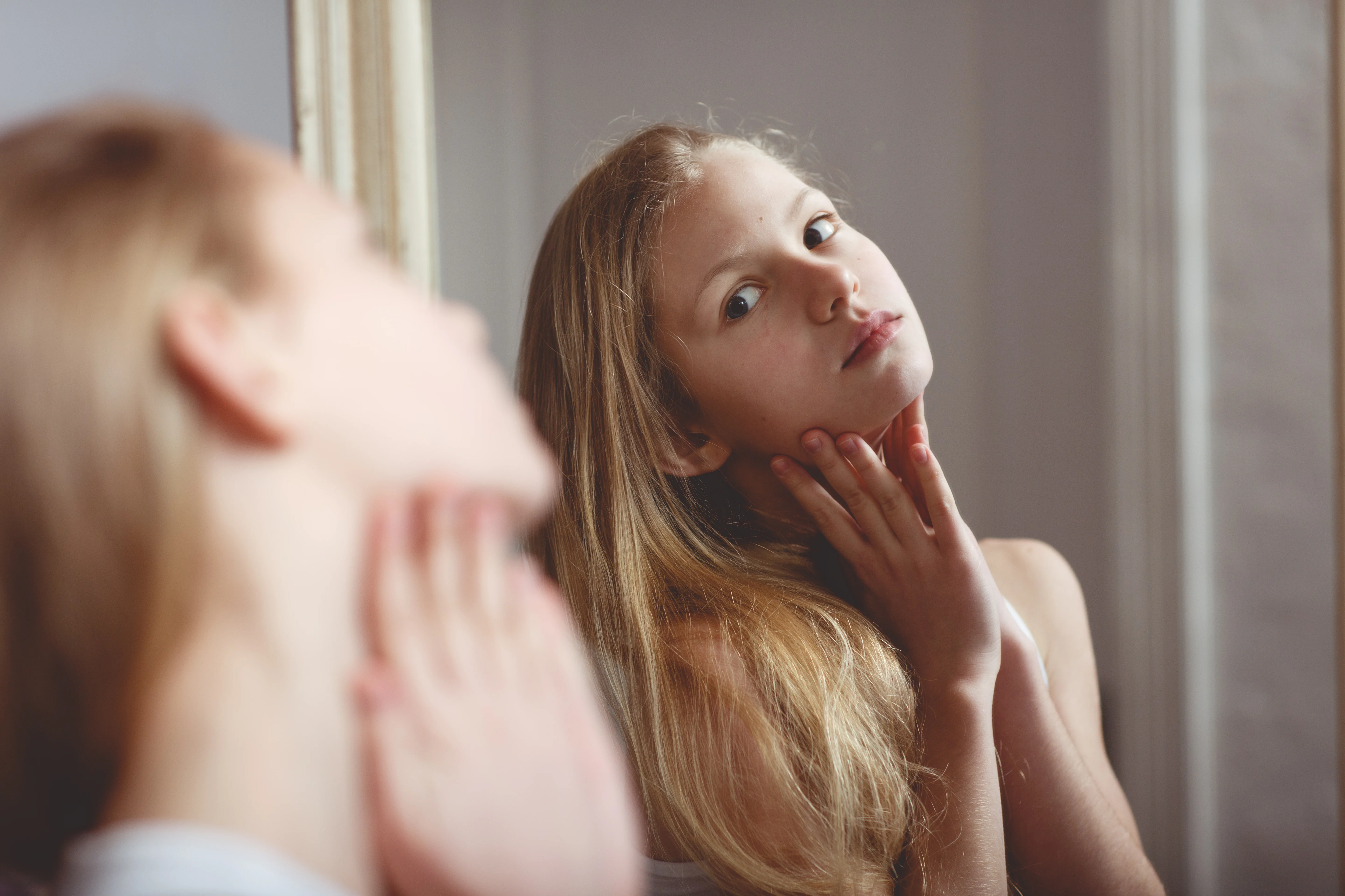 Young girl looking herself in the mirror