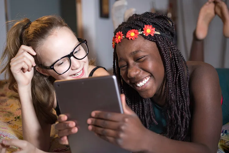 Two girls laughing while watching on tablet
