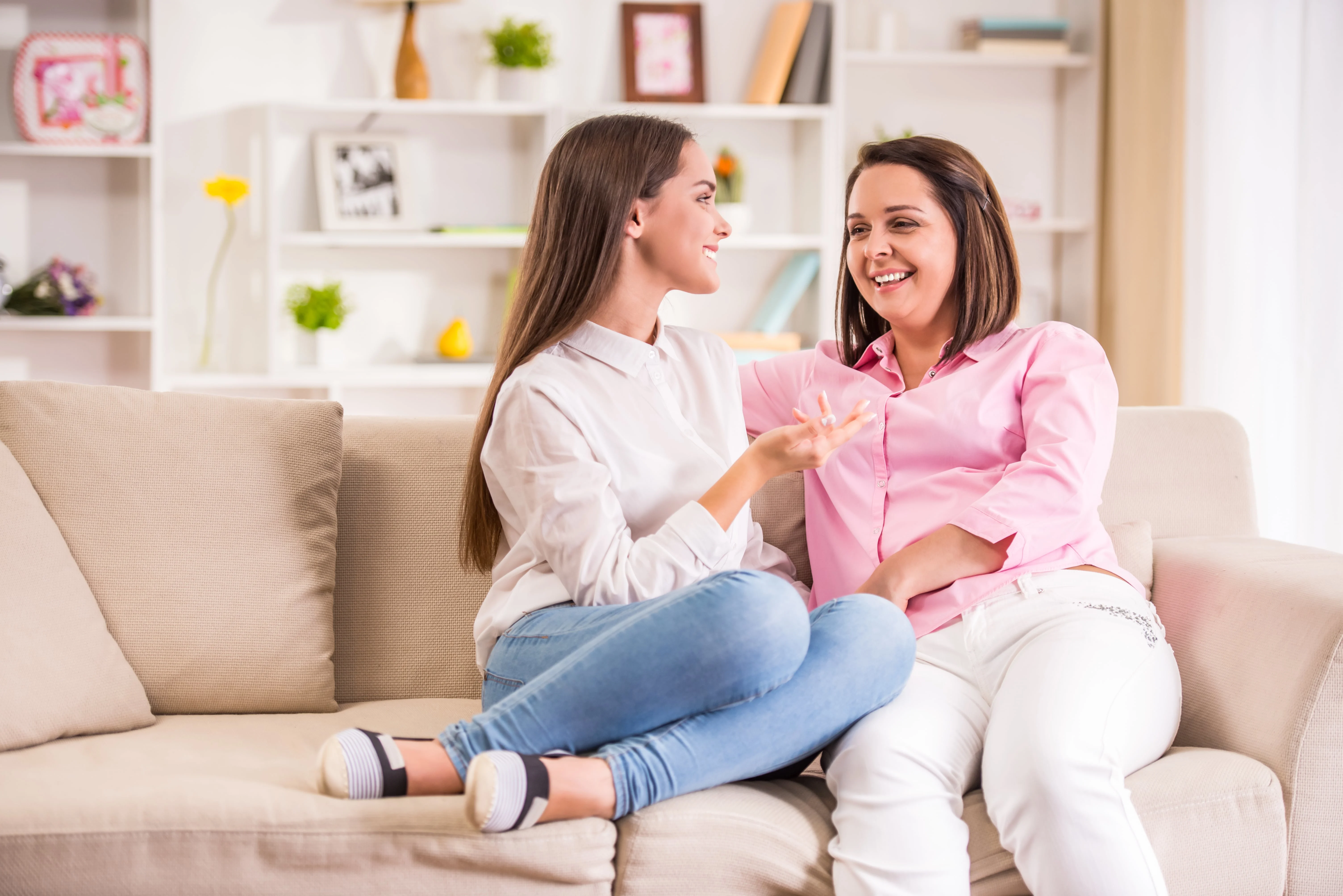 Daughter and mother talking while sitting on a couch