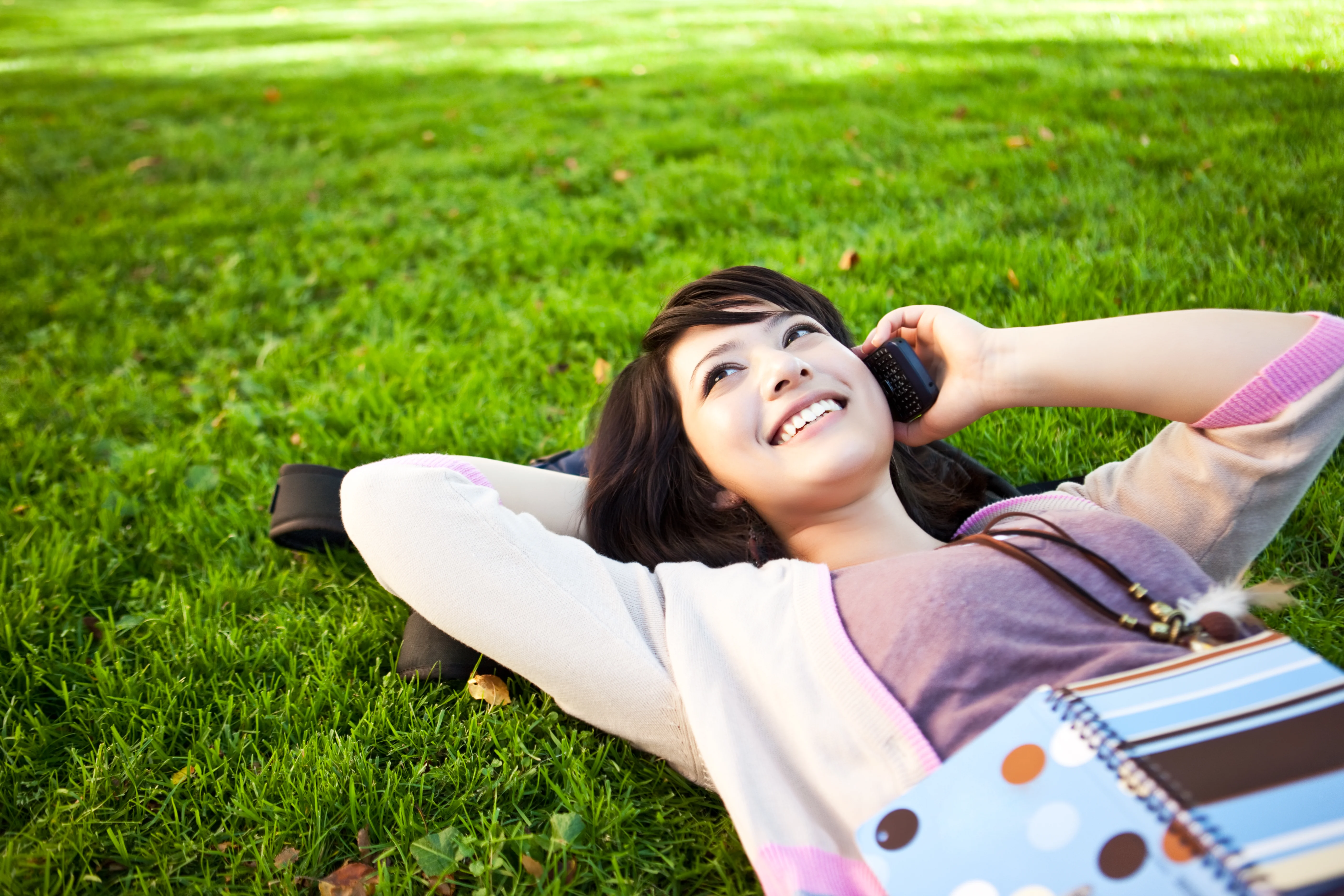 Woman lying on grass and talking on her phone