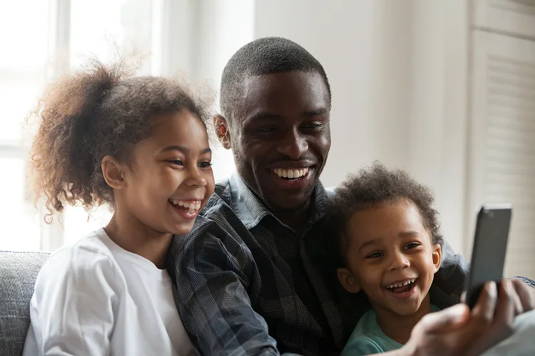 Father, daughter and son smiling while looking at a phone