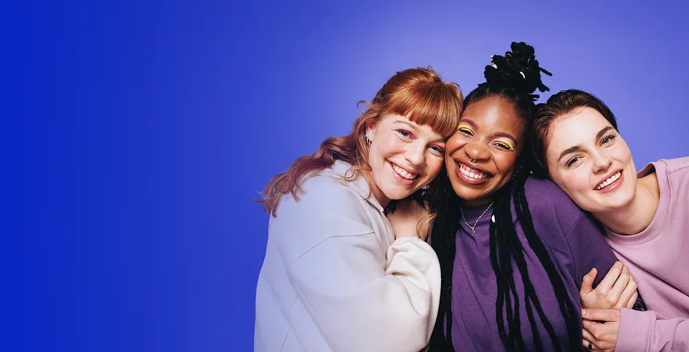 Three young women hugging and smiling next to the text period hub answer for all your questions on periods