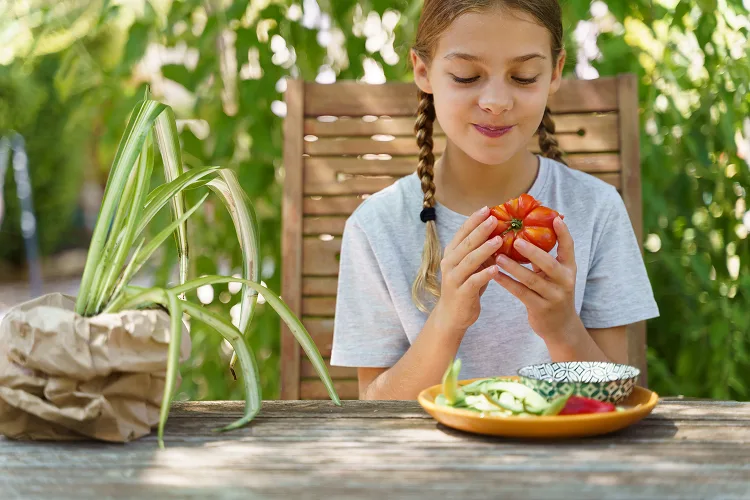 Girl sitting outside and holding a tomato