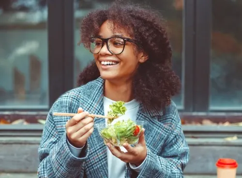 Young woman smiling holding a salad bowl