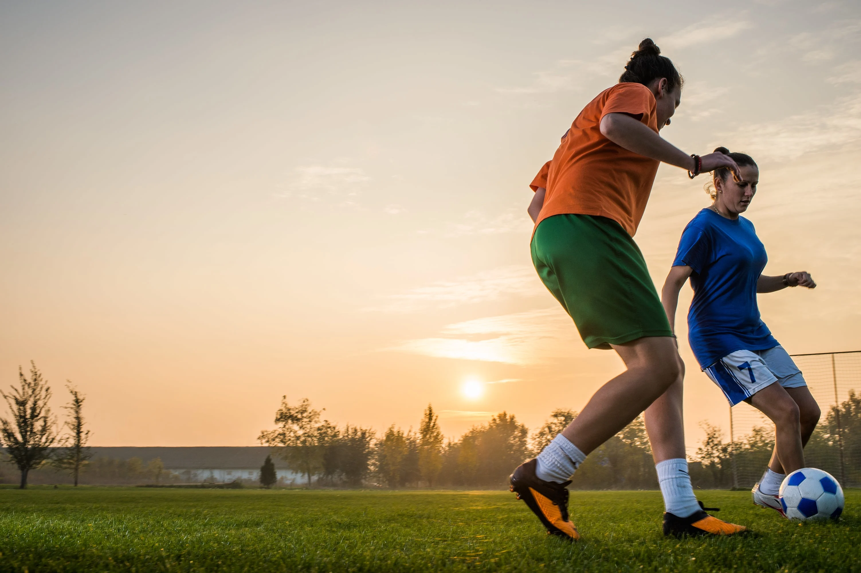 Two women playing football in the sunset