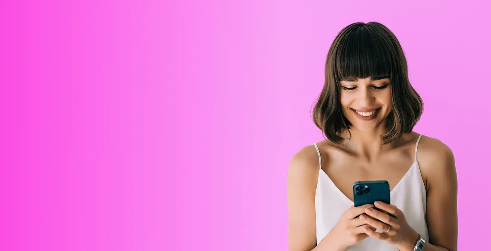 Smiling woman looking down at her smartphone using a period tracker