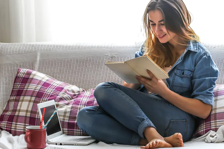 Girl reading a book on a cosy couch