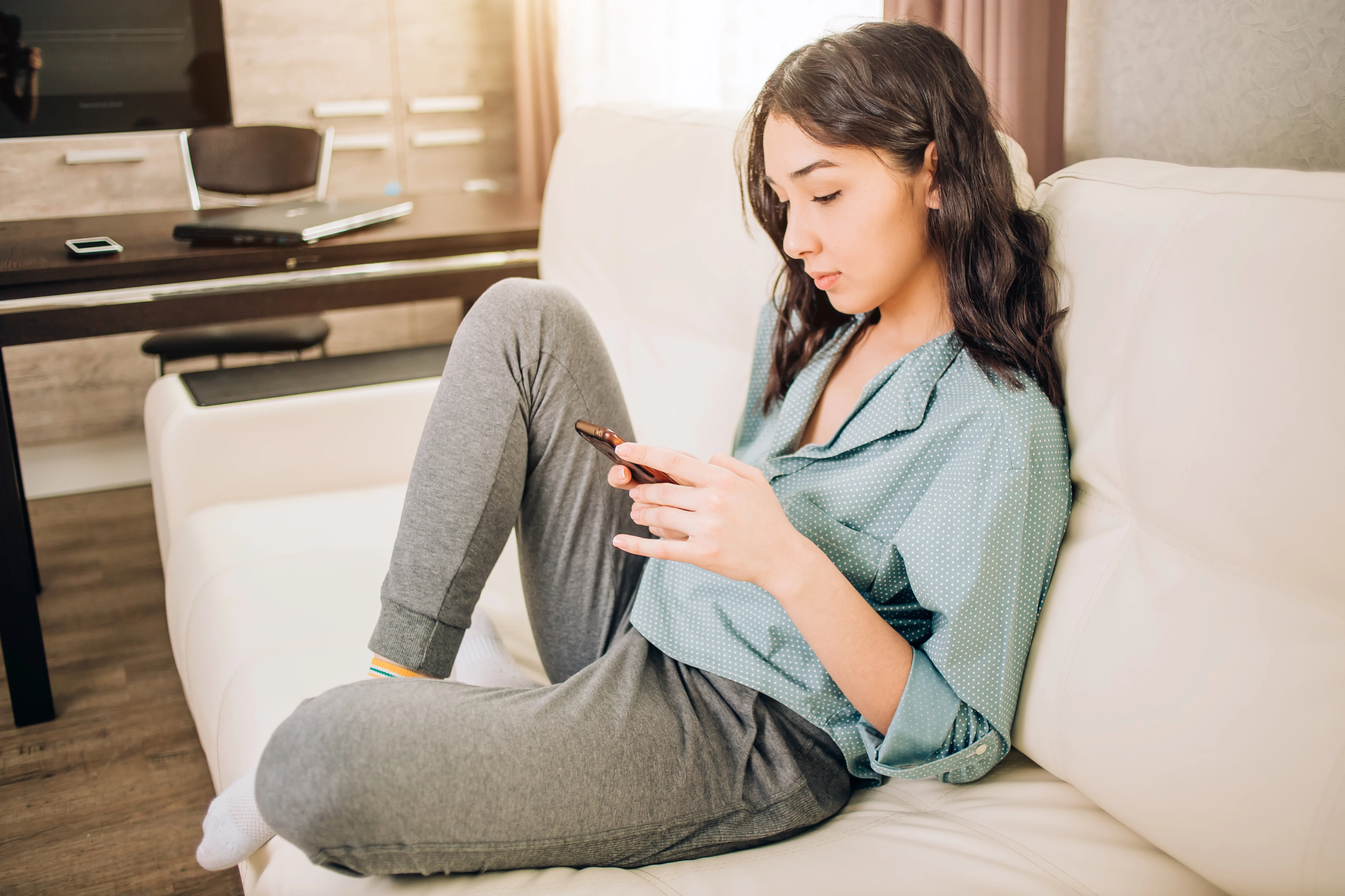 Girl sitting on a couch looking at her phone