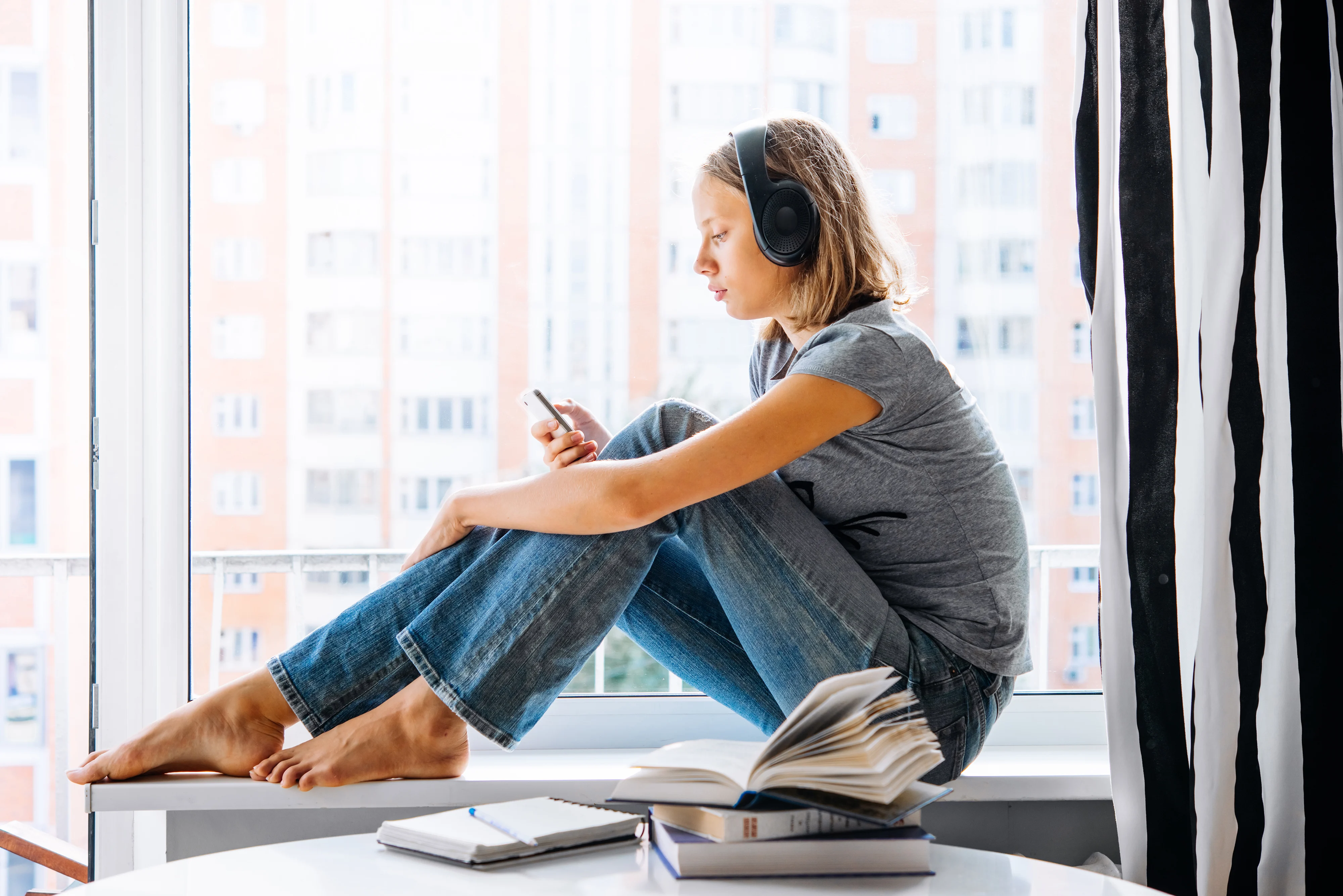 Girl sitting next to a window and listening to music