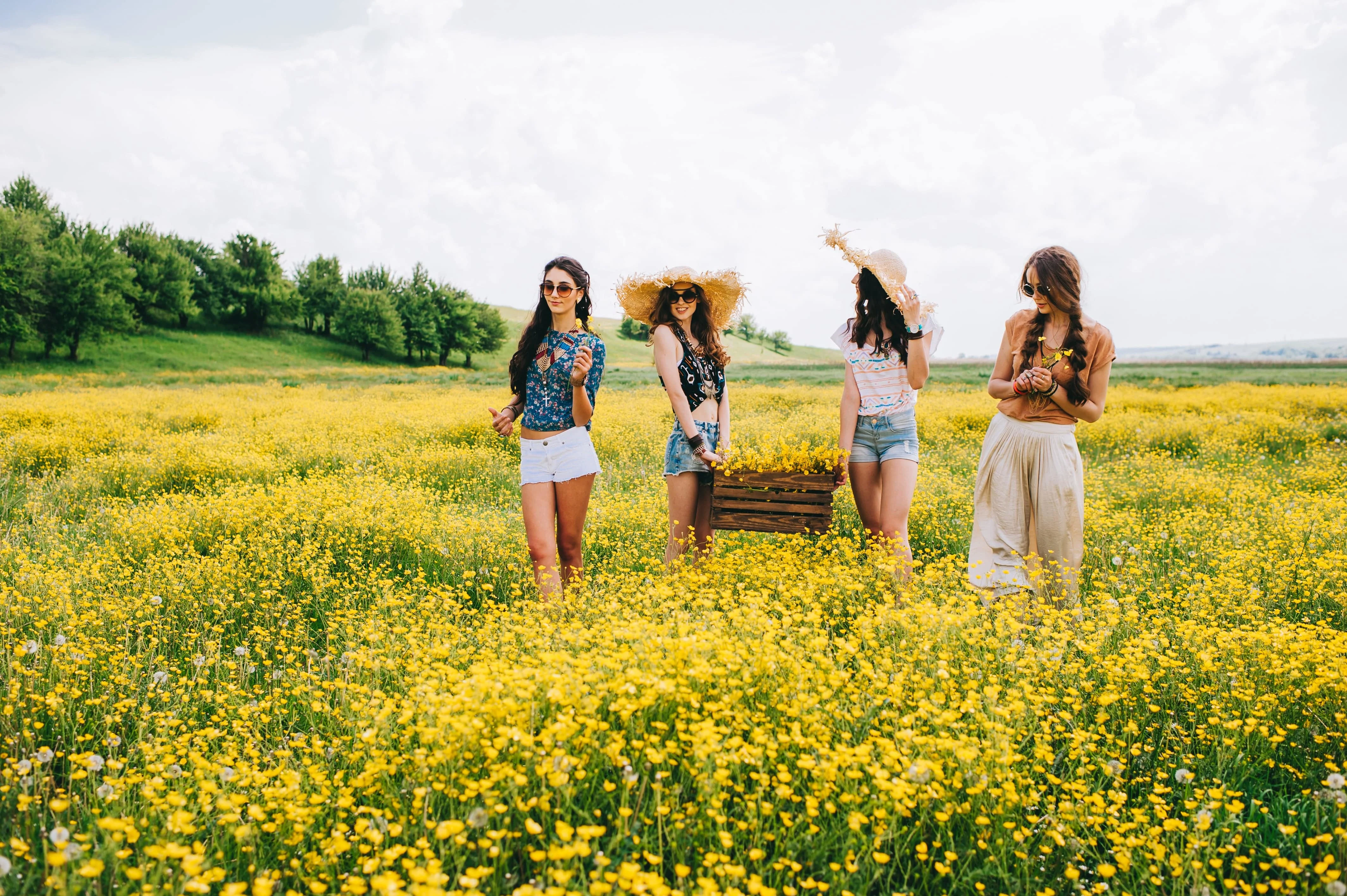Four women walking in a field of yellow flowers